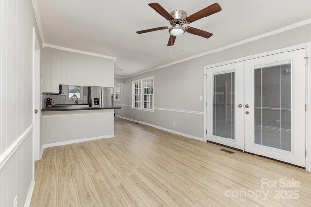 unfurnished living room featuring ceiling fan, light wood-style floors, french doors, visible vents, and ornamental molding