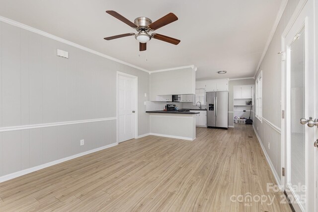 unfurnished living room with ornamental molding, baseboards, ceiling fan, a sink, and light wood-style flooring
