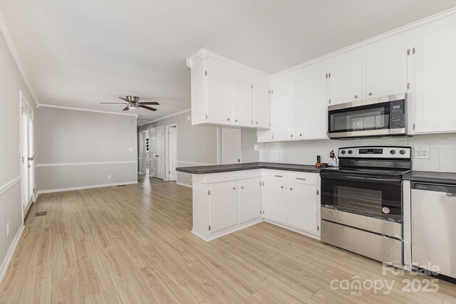 kitchen featuring dark countertops, a ceiling fan, stainless steel appliances, and a peninsula