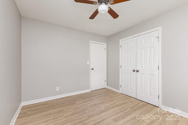 unfurnished bedroom featuring a closet, baseboards, a ceiling fan, and light wood-style floors