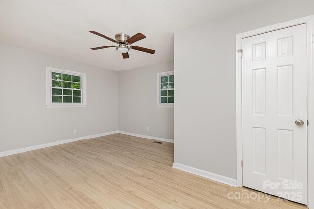 unfurnished room with ceiling fan, visible vents, baseboards, and light wood-style floors