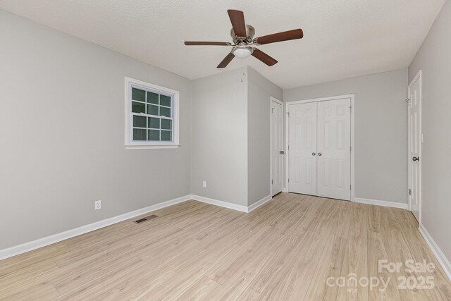 unfurnished bedroom featuring visible vents, baseboards, ceiling fan, and wood finished floors
