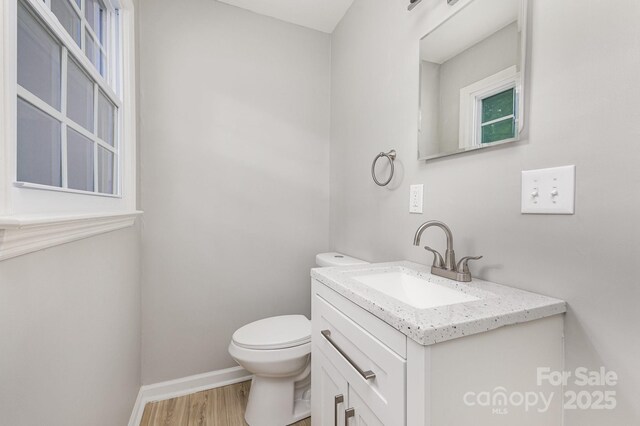 bathroom featuring vanity, baseboards, wood finished floors, and toilet