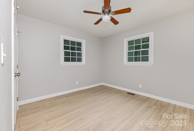 empty room with light wood-style floors, a ceiling fan, baseboards, and visible vents