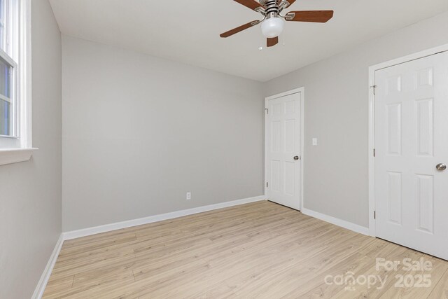 unfurnished bedroom with a ceiling fan, baseboards, and light wood-style flooring