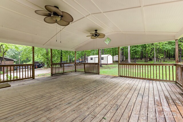 deck with an outdoor structure, ceiling fan, a shed, and a yard