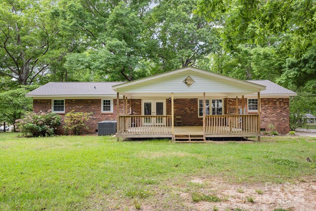 rear view of property featuring a deck, french doors, brick siding, central air condition unit, and a yard