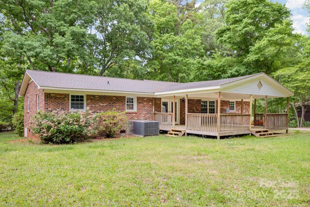 back of house featuring a shingled roof, brick siding, crawl space, central AC unit, and a yard