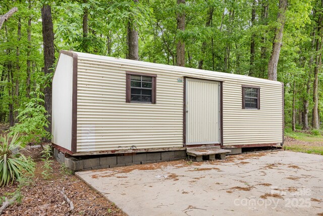 view of outbuilding featuring a wooded view, an outdoor structure, and entry steps
