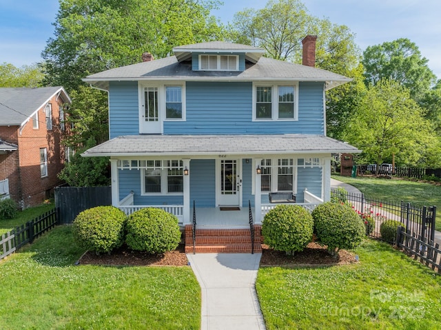 american foursquare style home with a porch, a front lawn, fence, and a chimney