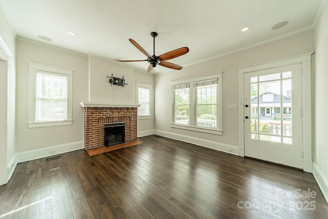 unfurnished living room with ceiling fan, visible vents, a brick fireplace, dark wood-style floors, and ornamental molding