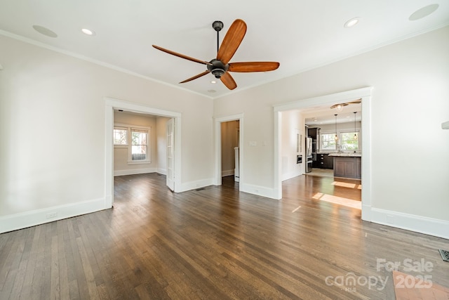 unfurnished living room featuring baseboards, dark wood finished floors, ceiling fan, and a wealth of natural light