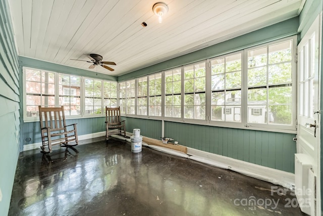 sunroom / solarium featuring ceiling fan, concrete floors, and baseboards