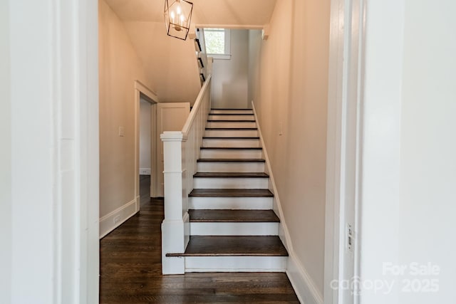 staircase featuring baseboards and wood finished floors