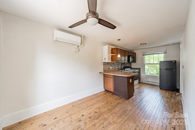 kitchen with light wood finished floors, a wall mounted air conditioner, a peninsula, a baseboard heating unit, and black appliances