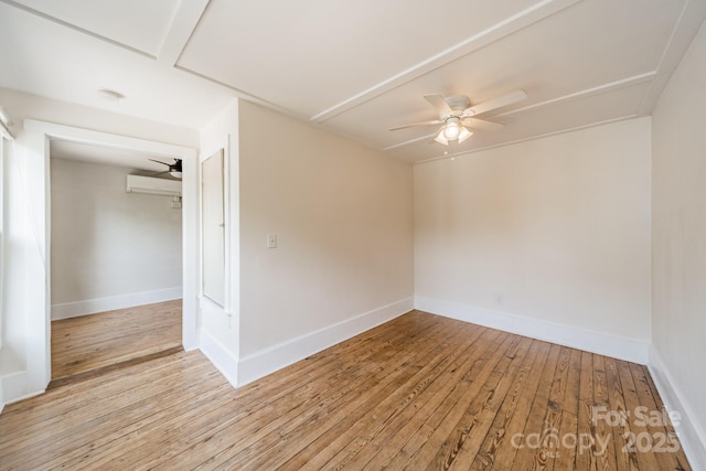 spare room with baseboards, a wall mounted AC, a ceiling fan, and light wood finished floors