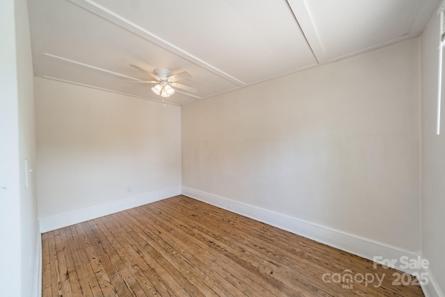 empty room featuring baseboards, attic access, a ceiling fan, and hardwood / wood-style floors