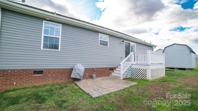 rear view of house with an outdoor structure, a patio, crawl space, a shed, and a lawn