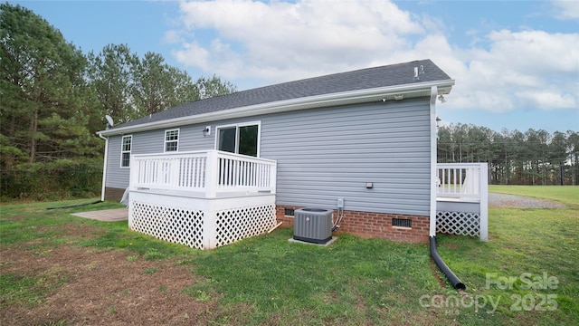 back of property with central air condition unit, crawl space, a shingled roof, a lawn, and a deck