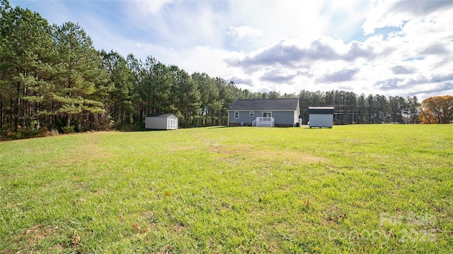 view of yard featuring a storage shed, a view of trees, and an outbuilding