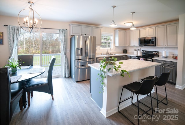 kitchen with tasteful backsplash, stainless steel appliances, light wood-style flooring, and a sink