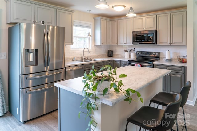 kitchen with gray cabinetry, a sink, stainless steel appliances, and light wood-style floors