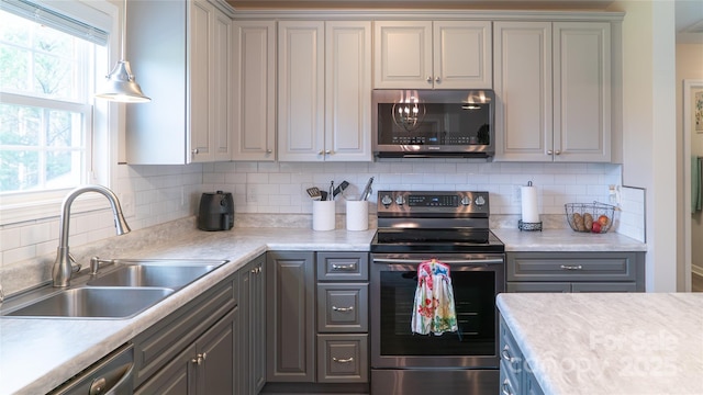 kitchen featuring a sink, gray cabinets, stainless steel appliances, and light countertops