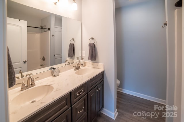 bathroom with wood finished floors, toilet, double vanity, and a sink