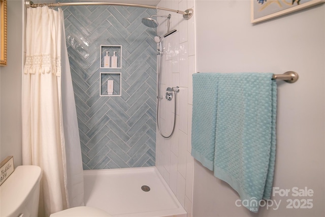 bathroom with a shower stall and toilet