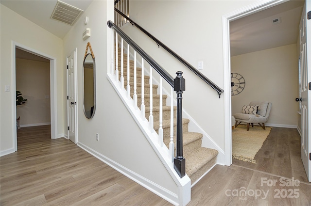 stairway with wood finished floors and baseboards