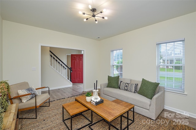 living area with a chandelier, wood finished floors, stairs, and baseboards