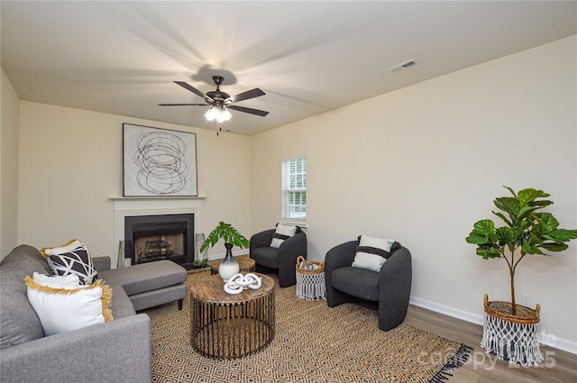 living room with wood finished floors, baseboards, a ceiling fan, and a fireplace