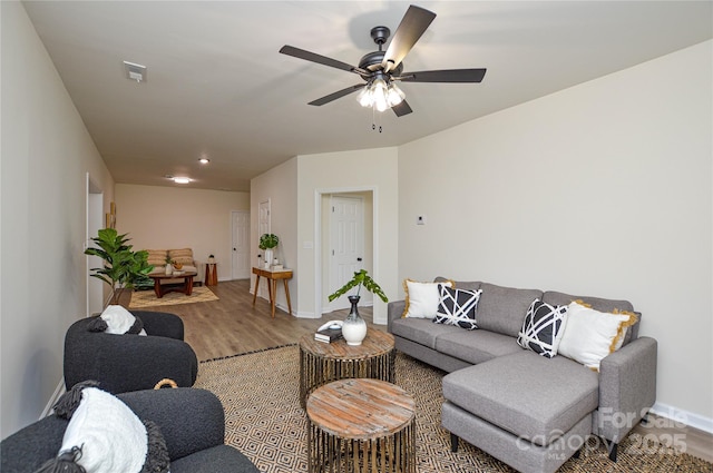 living room with light wood-type flooring, baseboards, and a ceiling fan