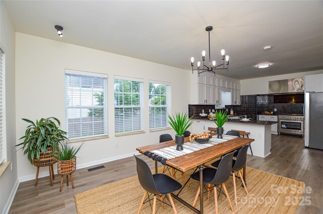 dining space featuring a chandelier, wood finished floors, and baseboards