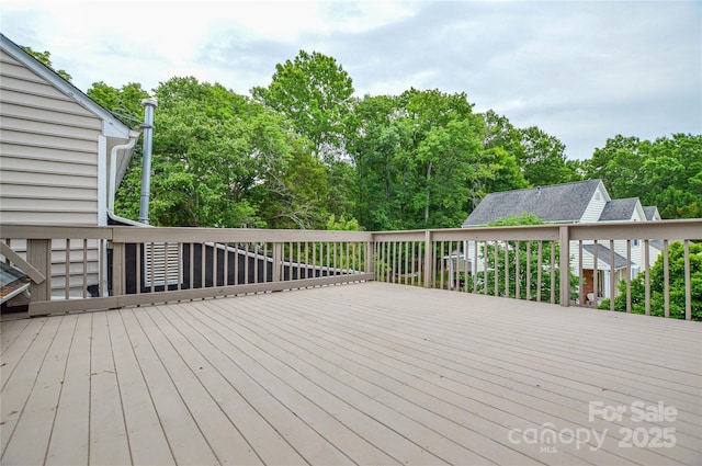 wooden terrace featuring view of wooded area