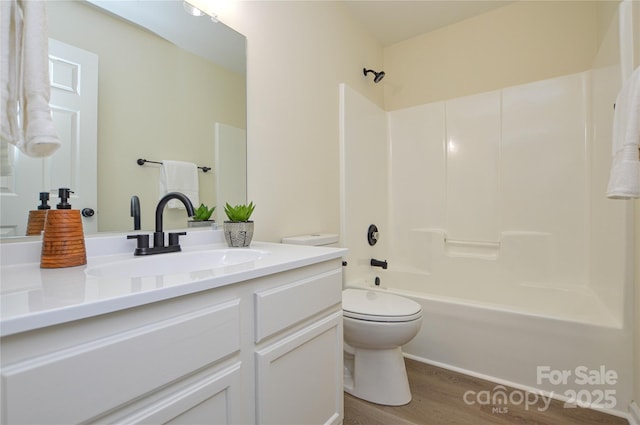 bathroom featuring wood finished floors, toilet, washtub / shower combination, and vanity