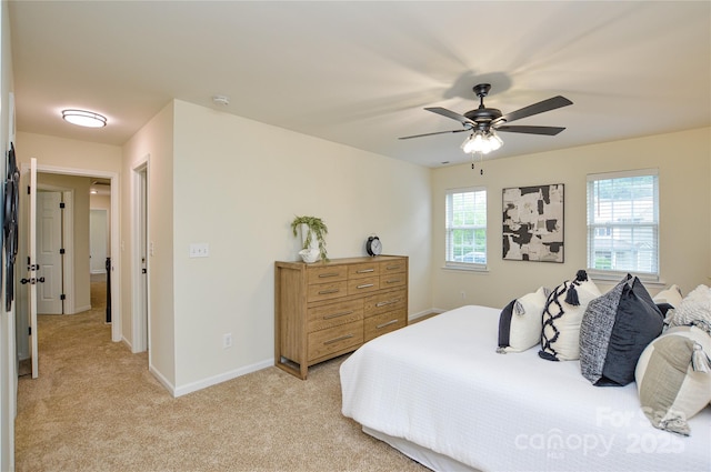 bedroom featuring light colored carpet, baseboards, and a ceiling fan