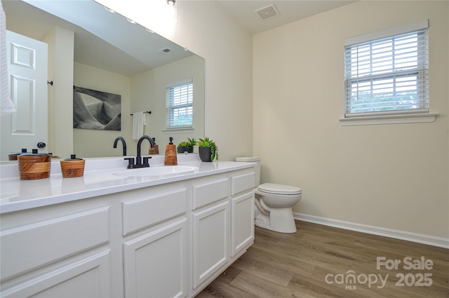 bathroom with wood finished floors, toilet, vanity, and baseboards
