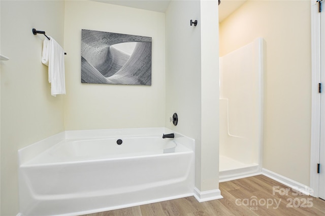 full bathroom featuring wood finished floors, a garden tub, baseboards, and a shower