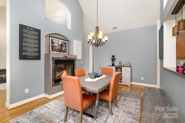 14807 Middlesborough Dr, Matthews, NC 28104 - dining room featuring wood finished floors, a tile fireplace, a chandelier, baseboards, and vaulted ceiling