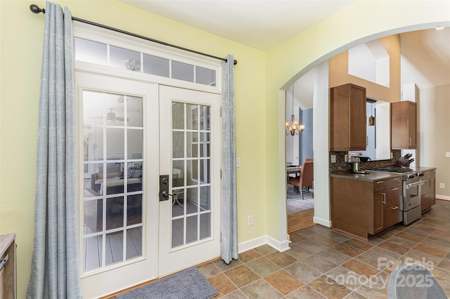 14807 Middlesborough Dr, Matthews, NC 28104 - doorway with french doors, baseboards, dark stone finish floors, arched walkways, and a chandelier