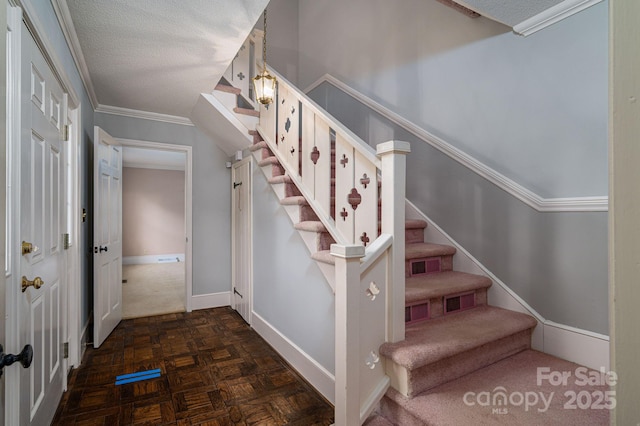 staircase with baseboards, ornamental molding, and a textured ceiling