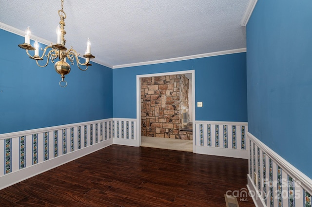 unfurnished room featuring ornamental molding, a textured ceiling, wood finished floors, and a notable chandelier