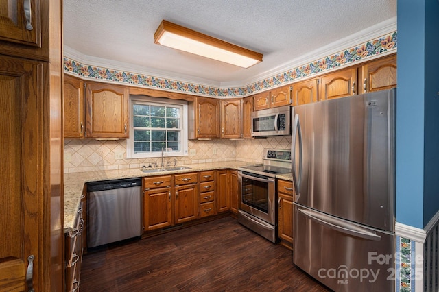 kitchen with a sink, dark wood finished floors, brown cabinetry, stainless steel appliances, and tasteful backsplash
