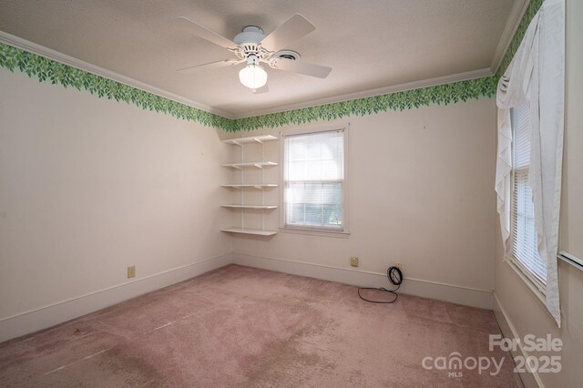 carpeted empty room with baseboards, ornamental molding, a textured ceiling, and ceiling fan