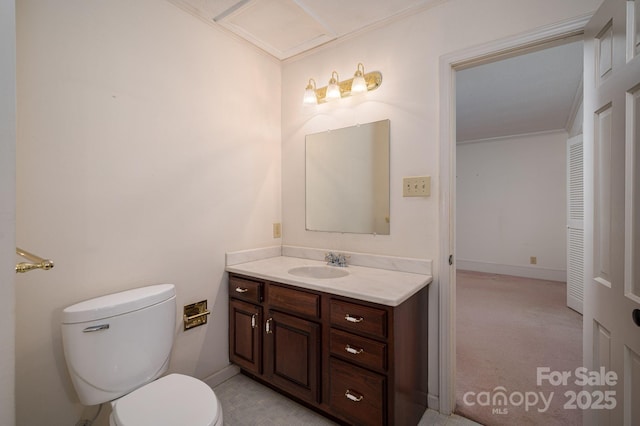 half bathroom featuring vanity, ornamental molding, baseboards, and toilet