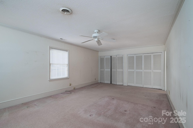 unfurnished bedroom featuring multiple closets, ornamental molding, and carpet flooring