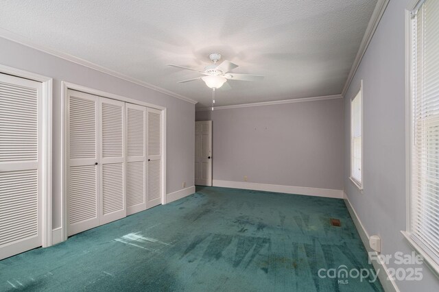 unfurnished bedroom featuring a ceiling fan, a textured ceiling, carpet floors, baseboards, and ornamental molding