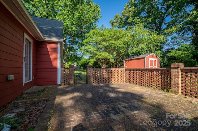 view of patio / terrace with fence, an outbuilding, a gate, and a shed
