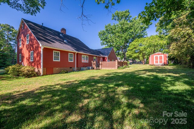 rear view of property with a storage shed, an outdoor structure, a chimney, and a yard